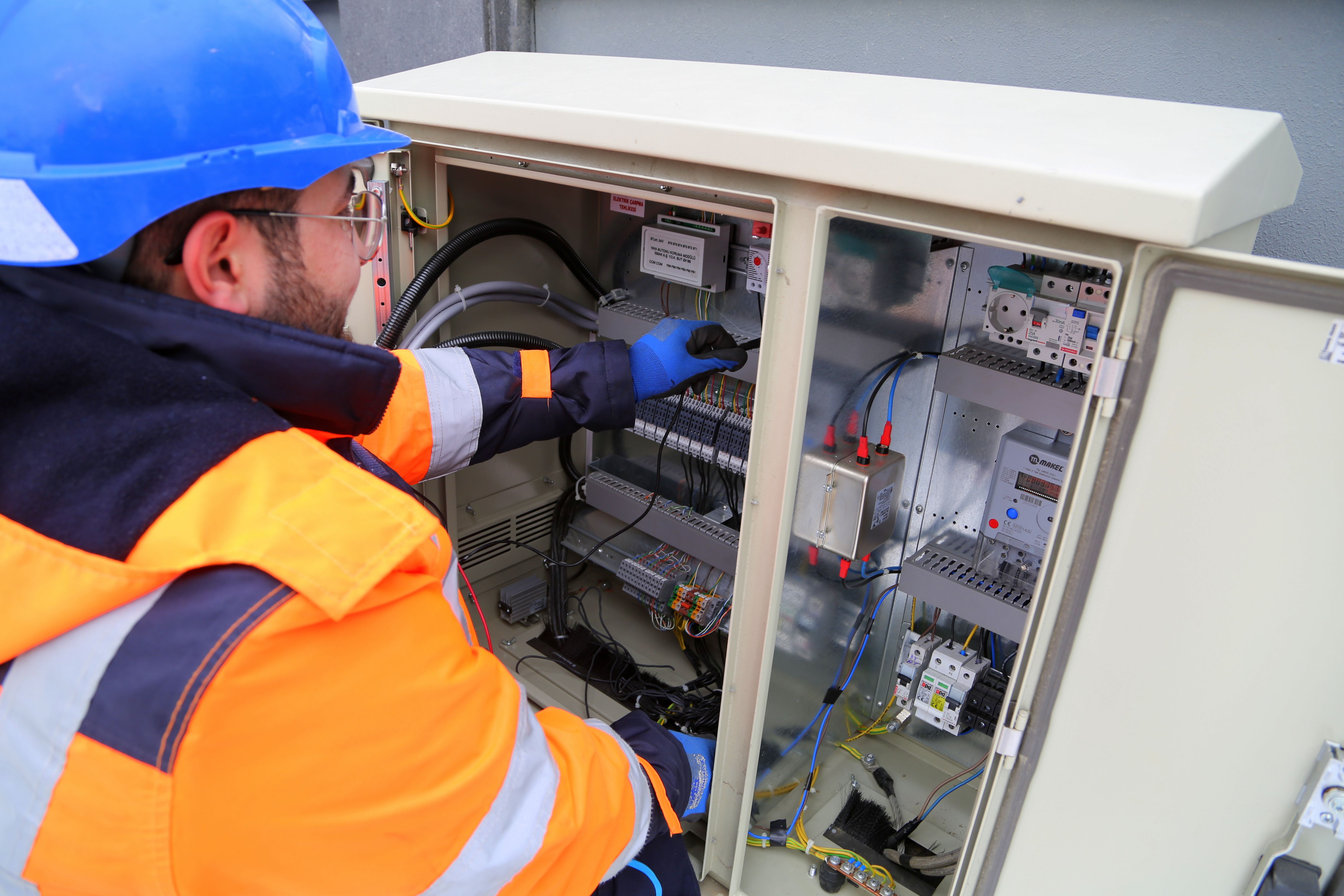 Commercial electrician testing wiring inside an electrical cabinet